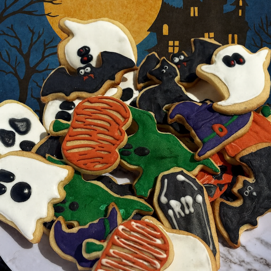 Halloween-themed cookies on a plate with a moon, bats, and castle in the background.
