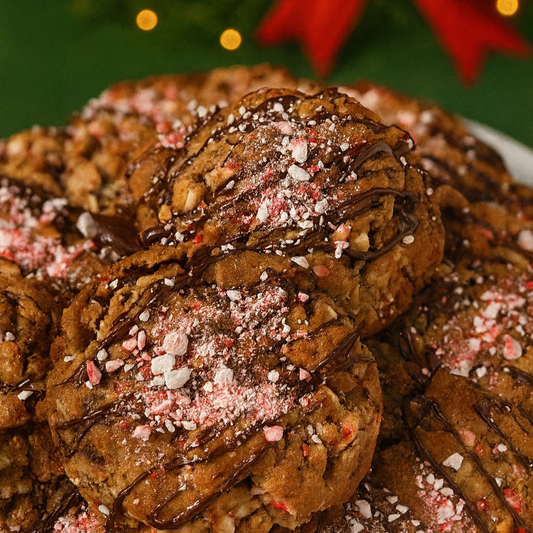 Stack of peppermint bark cookies on a plate, Christmas lights and bow in the background.
